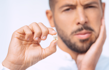 Man in pain holding up tooth