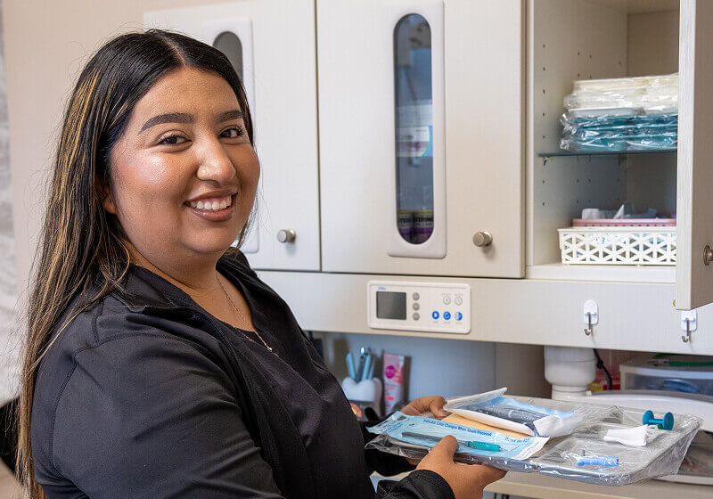 A staff member smiling while holding a tray of tools at Pocock Family Dental in Twin Falls ID.