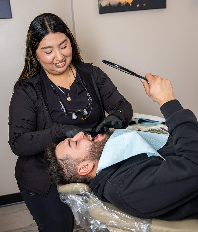 A staff member with a patient sitting in an exam chair while looking in a mirror at Pocock Family Dental in Twin Falls ID.
